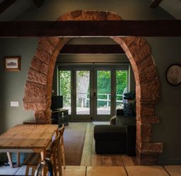 A living room with an arch leading to outdoor space at Carwinley Mill House Cottage Carwinley near Longtown