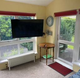 A conservatory with a television and table at Kenvor Newport, Pembrokeshire