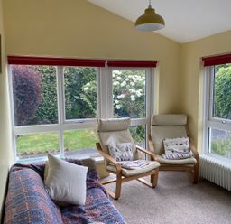 A sunroom with a sofa and armchairs at Kenvor in Newport, Pembrokeshire