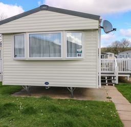 An outdoor view of a mobile home with a satellite dish at 82 Manorbier Park in Manorbier