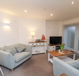 A living room with a sofa, lamp, and television at One Union Mill - garden apartment in Whitby