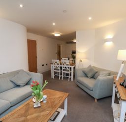 A living room with a sofa and dining area at One Union Mill - garden apartment Whitby