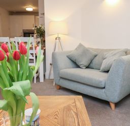 A living room with a sofa and flowers at One Union Mill - garden apartment in Whitby