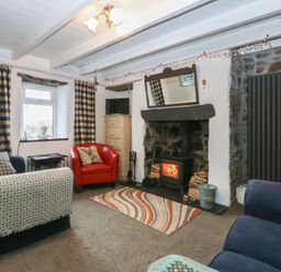 A living room with a fireplace and seating area at Parc y Brenin Holidays, Abersoch