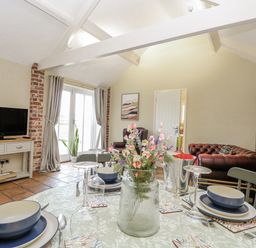 A living room with a television and dining table at Ivy Barn in Norwich