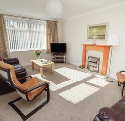 A living room with a television and seating arrangements at Kittiwake at No 20 in Seahouses