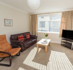 A living room with a sofa and coffee table at Kittiwake at No 20 Seahouses