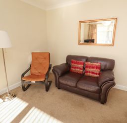 A living room with an armchair and couch at Kittiwake at No 20 Seahouses