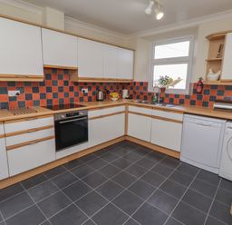A kitchen with cabinets, oven, sink, and washing machine at Kittiwake at No 20 Seahouses