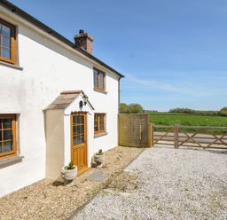 An outdoor view of a house with a gravel path and fence at Little Blagdon Ashwater