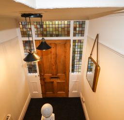 A hallway with a wooden door and stained glass windows at Waterhead Cottage in Ambleside