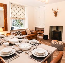 A dining room with a table set for dinner at Waterhead Cottage, Ambleside