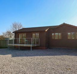 A house with a deck and gravel area at Star Carr Lakes