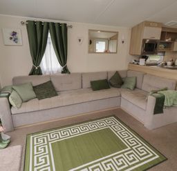 A living room with a sofa and kitchen unit at Homeslea 33 Millennium Gardens Morpeth
