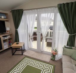 A living room with a television and sliding doors at Homeslea 33 Millennium Gardens in Morpeth