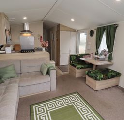 A living room with a sofa, dining table, and kitchen appliances at Homeslea 33 Millennium Gardens in Morpeth