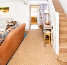 A living room with a sofa and staircase at Gardeners Cottage in Chipping Norton