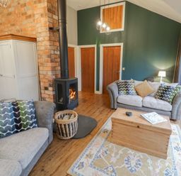 A living room with a stove and sofa at Otter's Rest in Droitwich