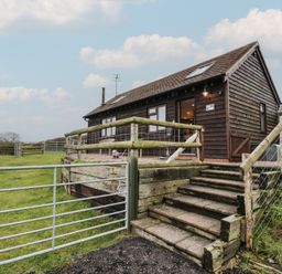 A cabin with steps leading to a fenced outdoor area at The Barn on The Lagoon Droitwich