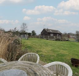 An outdoor area with a table and chairs near a house at The Barn on The Lagoon Droitwich