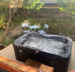 An outdoor space with a hot tub, table, and chairs at The Hermitage in Penrith