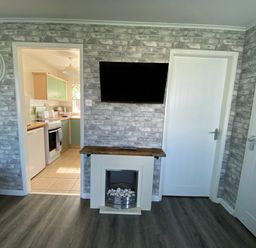 A living room with a television and fireplace at Chalet 58 in California, Norfolk