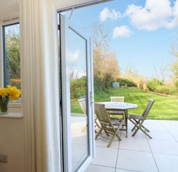A dining area with a table and chairs overlooking a garden at The Pebble in Dorchester