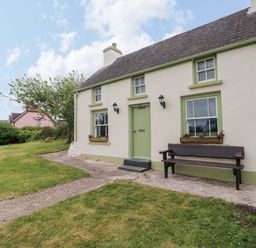A cottage with a green door and bench at Beacon House in Marloes near Little Haven