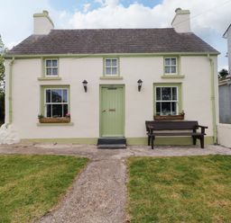 A cottage with a green door and windows at Beacon House Marloes near Little Haven