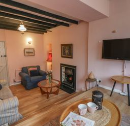 A living room with a sofa and television at 1 Alpha Cottages in Tenby