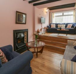 A living room with a fireplace and seating at 1 Alpha Cottages in Tenby