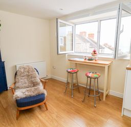 A kitchen with stools and a table near an open window at Flat 3 