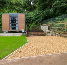 An outdoor view of a mobile cabin with gravel and steps at The Pod in Ferryside