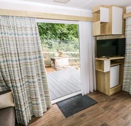 A living room with a sliding door and television at The Pod in Ferryside