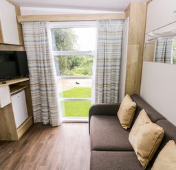 A living room with a television, sofa, and window at The Pod in Ferryside