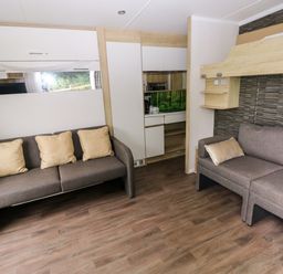 A living room with two sofas and a kitchen area at The Pod in Ferryside