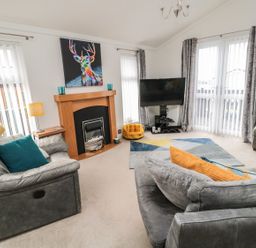 A living room with a television and fireplace at Nevaeh Lodge Longframlington