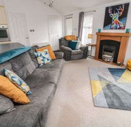 A living room with a sofa and armchair at Nevaeh Lodge in Longframlington