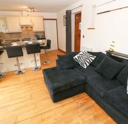 A living room with a sofa and bar stools at Red Kite Cottage in Haverfordwest