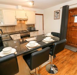 A kitchen with countertops and stools at Red Kite Cottage Haverfordwest