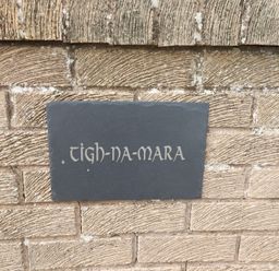 A slate sign with the name Tigh-Na-Mara on a wall