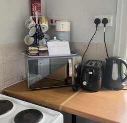 A kitchen with a microwave, toaster, kettle, mugs, and sugar packets at Chalet - Buckland 16 in Bideford