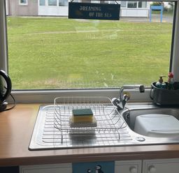 A kitchen sink with a dish rack and cleaning supplies at Chalet - Buckland 16 in Bideford