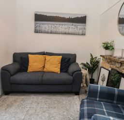 A snug with a gray sofa and yellow cushions at The Cottage Budleigh Salterton