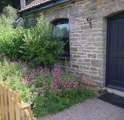 An outdoor area with flowers and a wooden gate at Castle Rag in Parkend