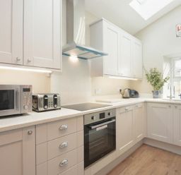 A kitchen with cabinets and appliances at Juniper Cottage