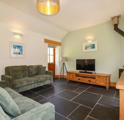 A living room with a sofa and television at Little Trethellan in Trethellan near Lanner