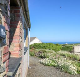 A view of Casa Mia with a garden and ocean in the background at Casa Mia Goodwick