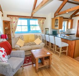 A living room with a sofa and kitchen area at Casa Mia Goodwick