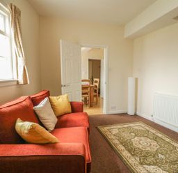A living room with a sofa and dining area at Cottage No 9 in Keswick